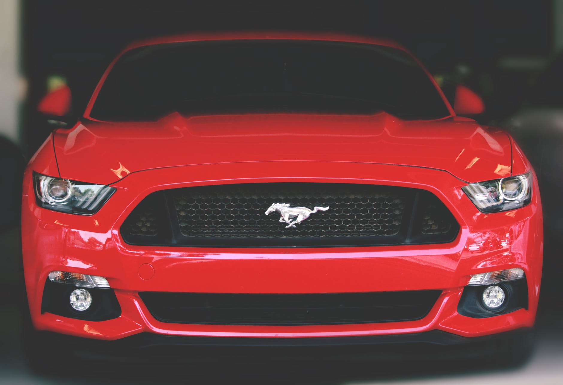 Front view of red Ford Mustang car showing the prancing Mustang horse on the front grill.
